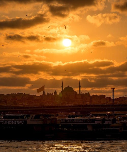 Sunset over Istanbul in Türkiye with mosque silhouette, Bosphorus waters and boats